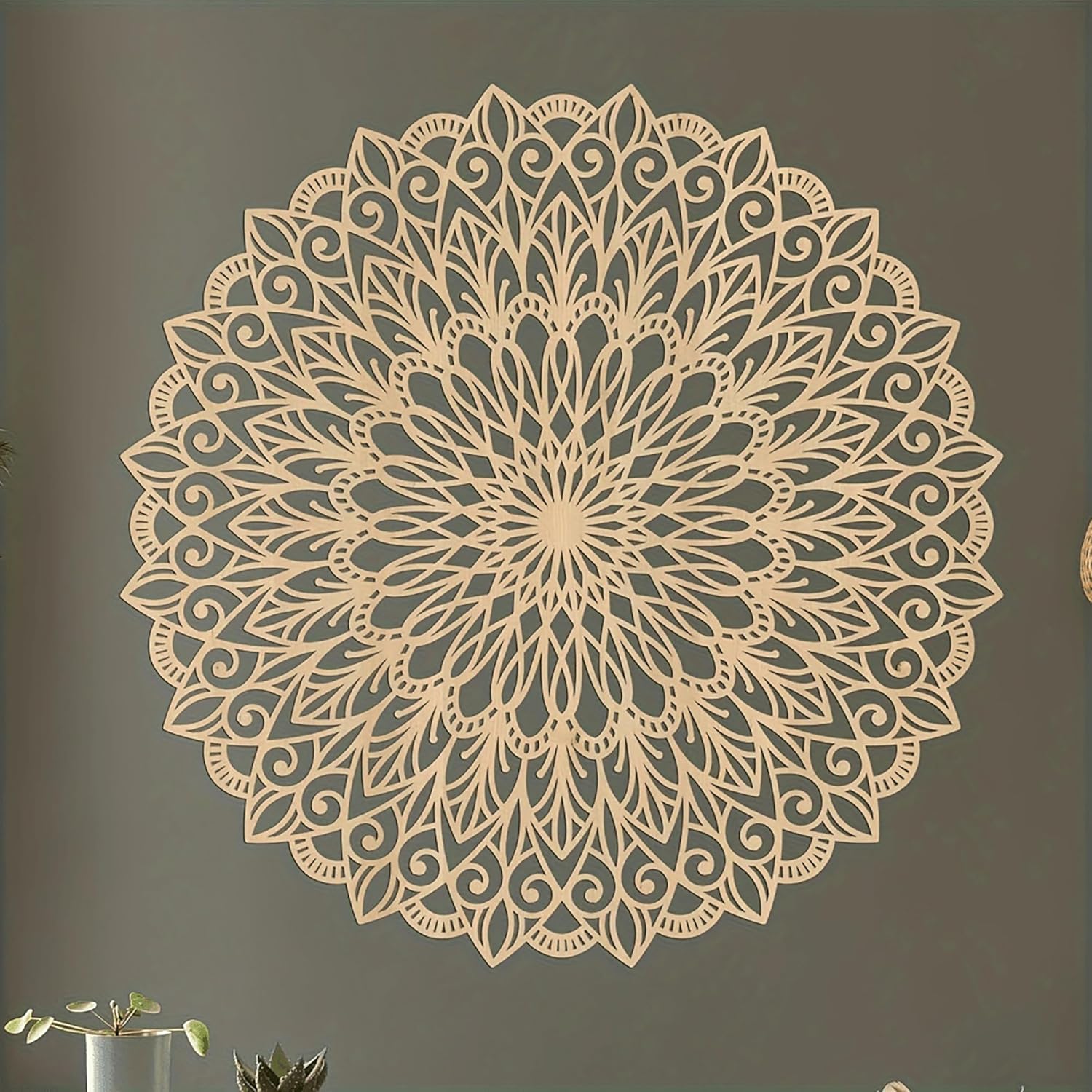 Decorative wall mandala on a plain wall with a plant in the corner.