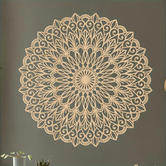 Decorative wall mandala on a plain wall with a plant in the corner.