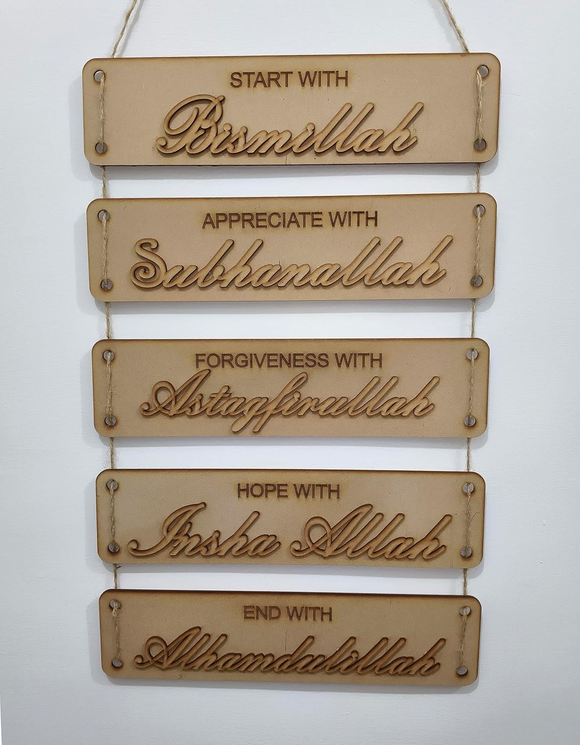 Wooden wall hanging with engraved phrases on a white background