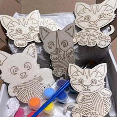 Wooden cat-shaped cutouts with paint supplies on a white surface