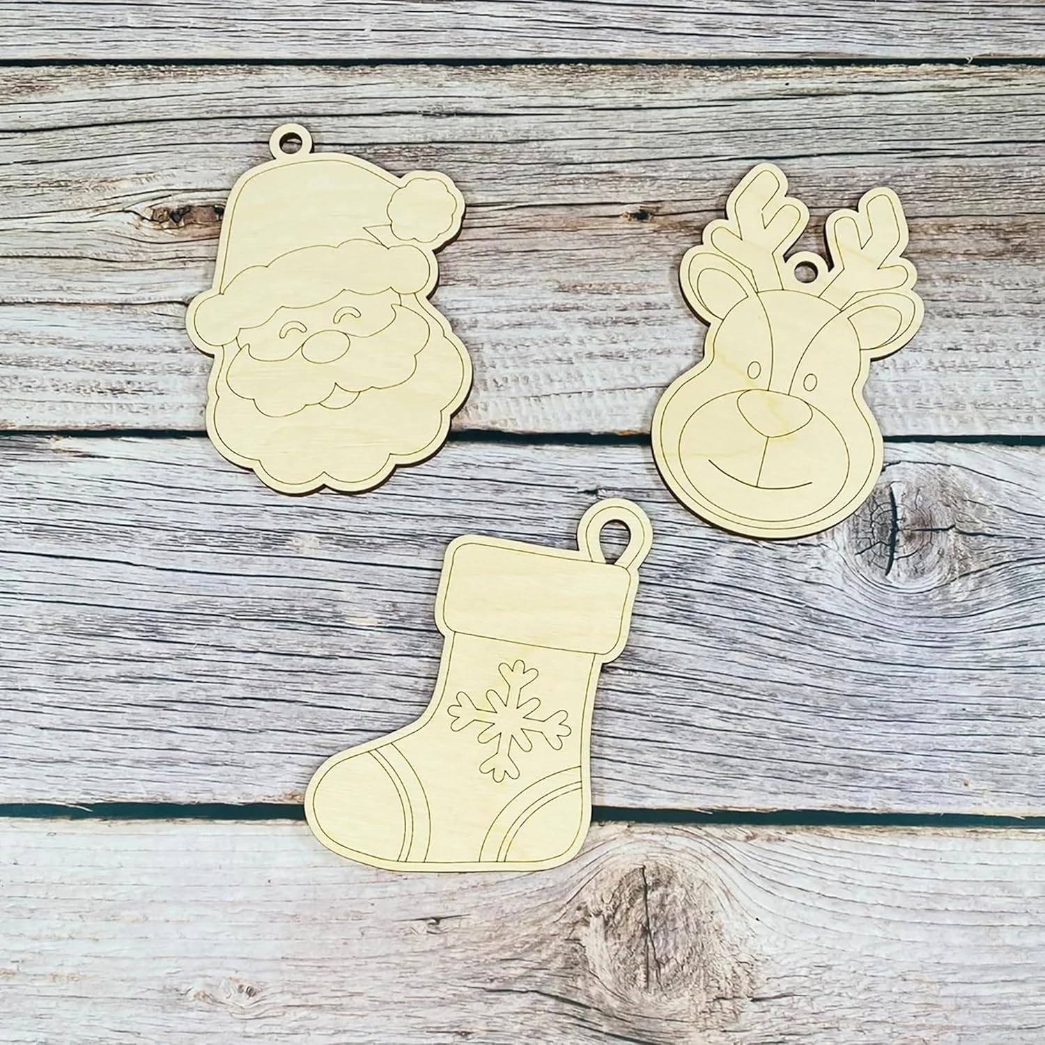 Three wooden Christmas ornaments shaped like Santa, a reindeer, and a stocking on a wooden surface.