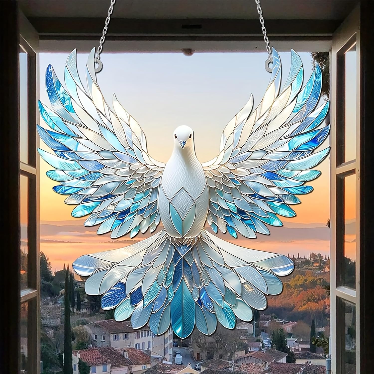 Stained glass dove hanging in front of a window with a scenic view.