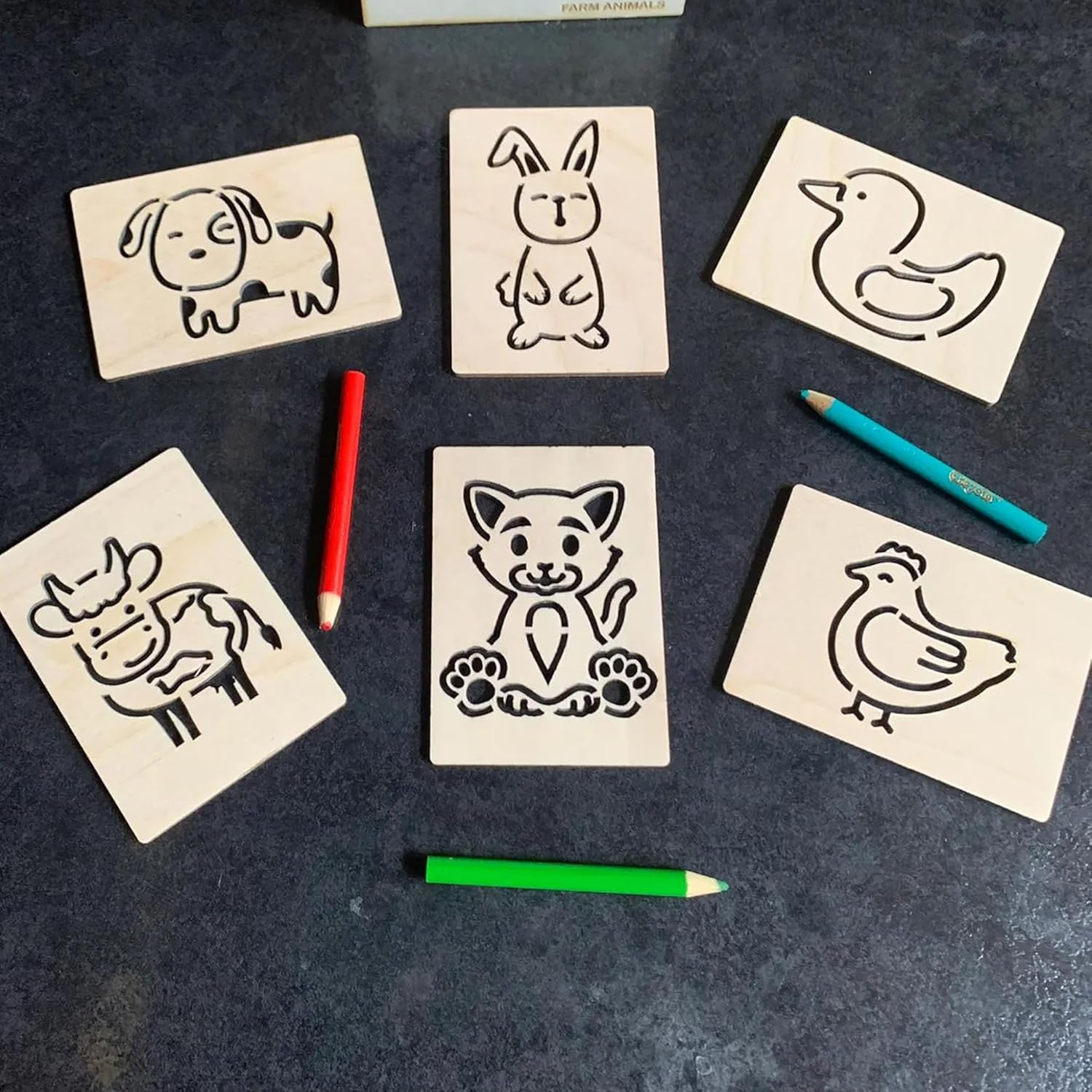 Set of wooden stamps with animal designs on a dark surface with colored pencils.