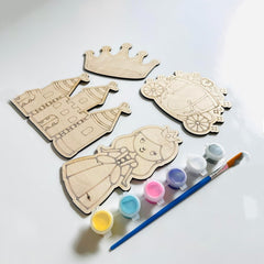 Wooden princess and castle cutouts with paint containers and a brush on a white background