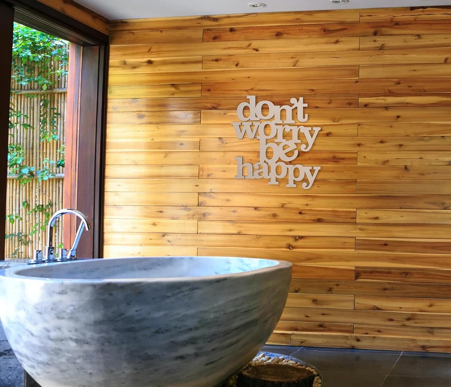 Marble bathtub in a bathroom with wooden wall and 'don't worry be happy' quote