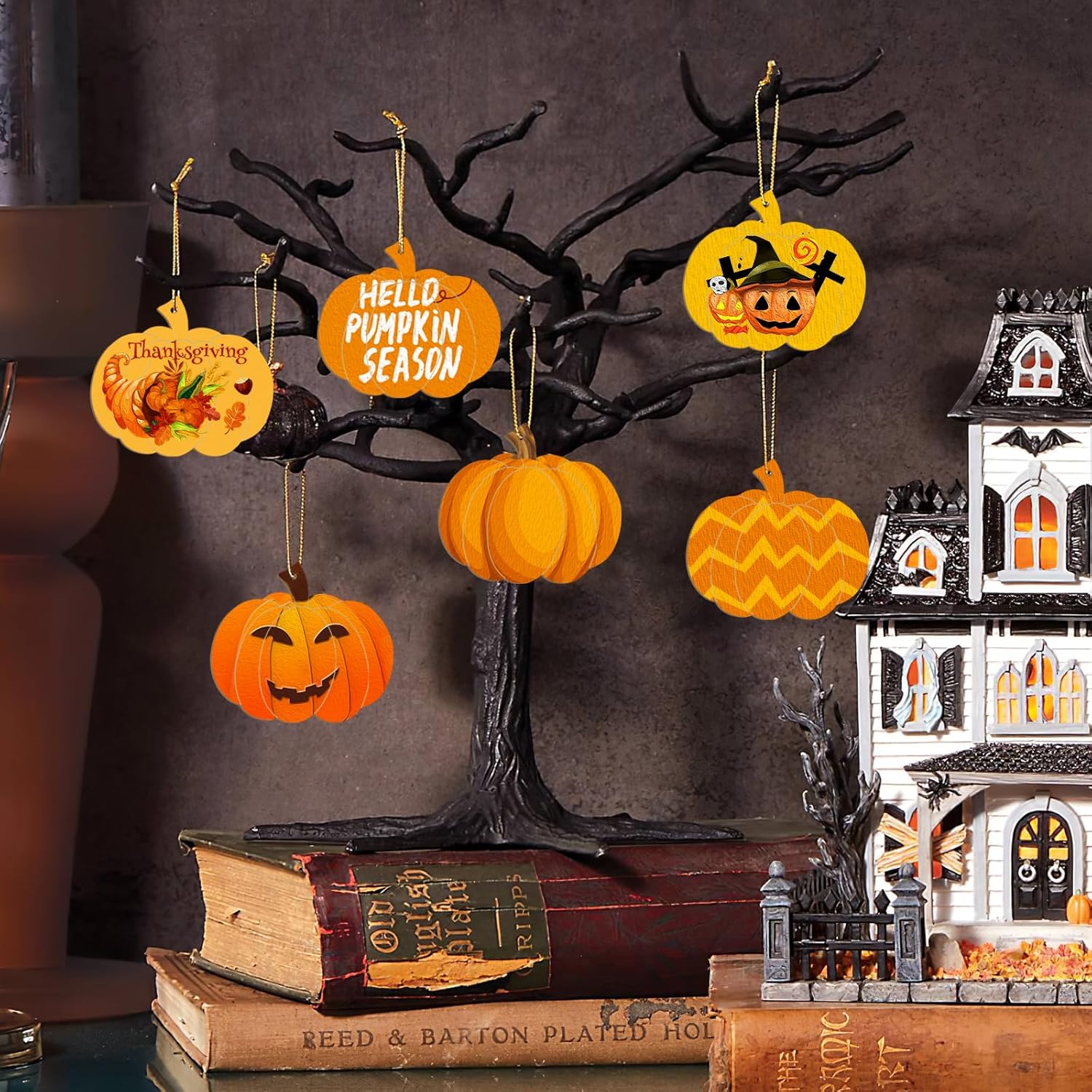 Halloween decorations including pumpkins and a haunted house model on a dark background.