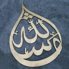 Decorative metal art piece with Arabic calligraphy on a blue fabric background