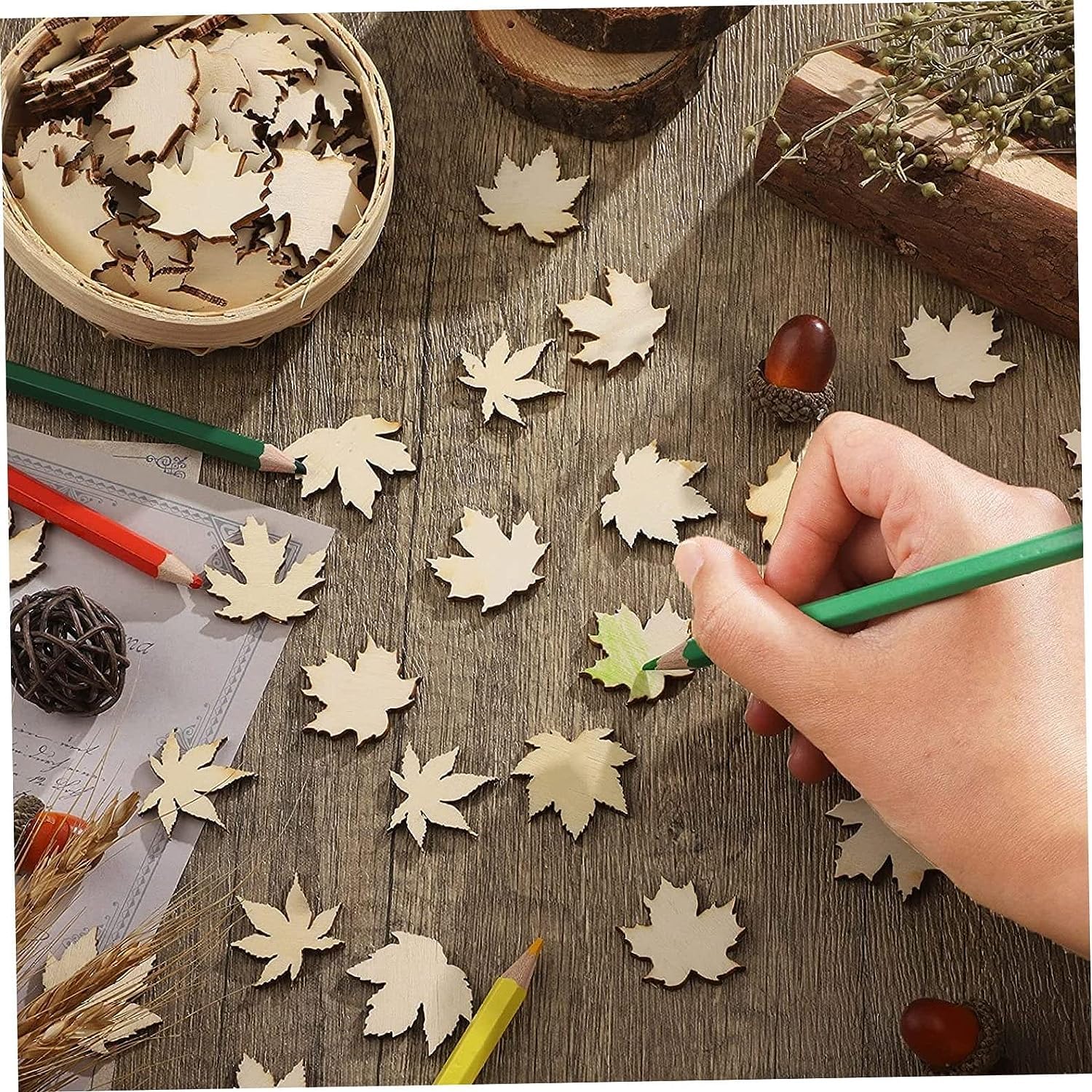 Hand painting wooden leaf shapes on a rustic wooden surface with natural elements.