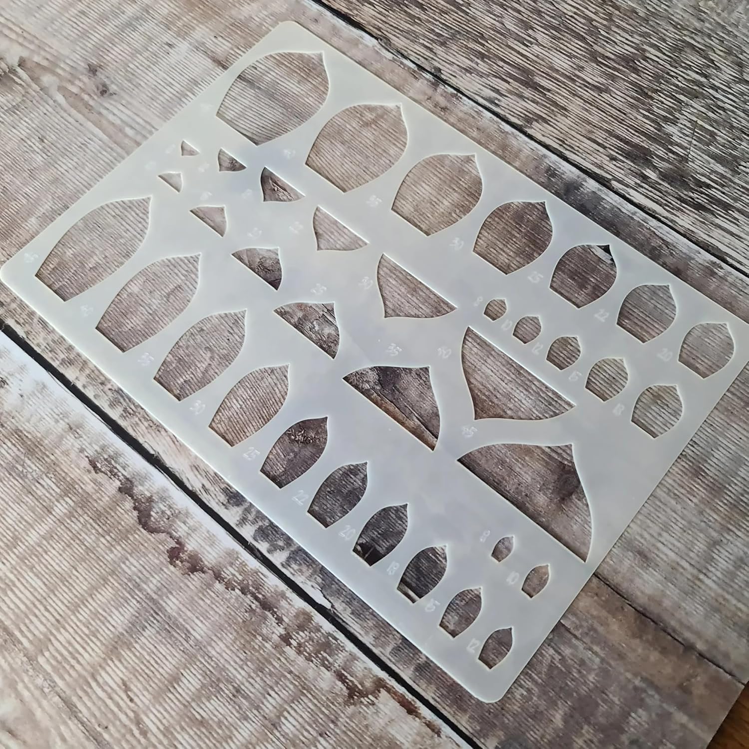 Decorative metal stencil with geometric cut-out design on a wooden surface