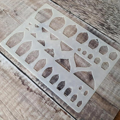 Decorative metal stencil with geometric cut-out design on a wooden surface