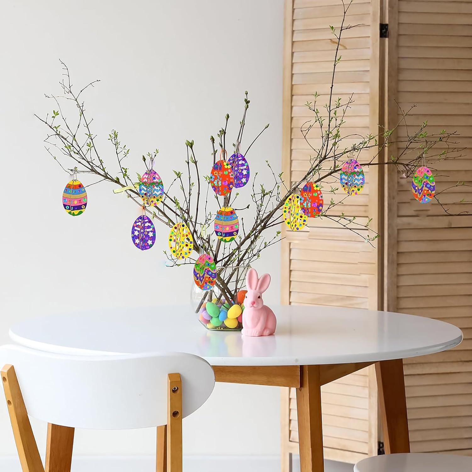 Decorative Easter setup with branches, colorful eggs, and a rabbit figurine on a table.