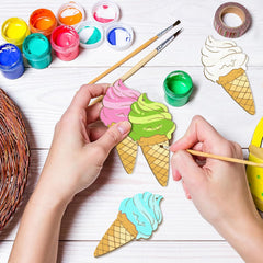 Children painting ice cream cone crafts with colorful paint and brushes on a wooden surface.