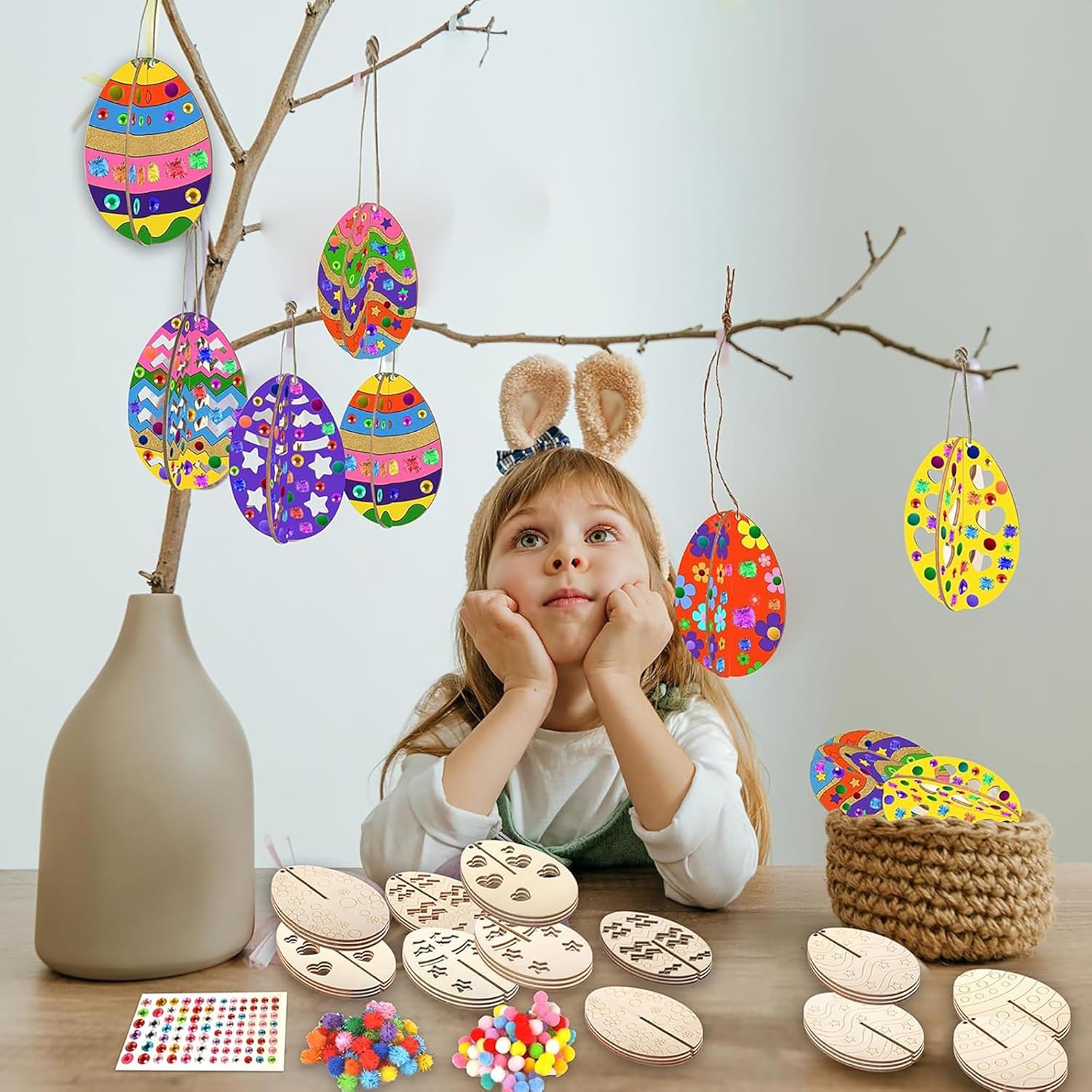 Child wearing bunny ears with colorful Easter egg decorations and craft materials on a table.