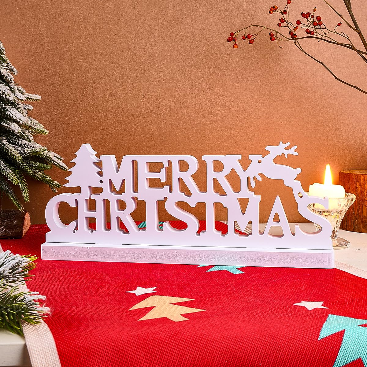 Decorative 'Merry Christmas' sign with reindeer and trees on a red tablecloth.