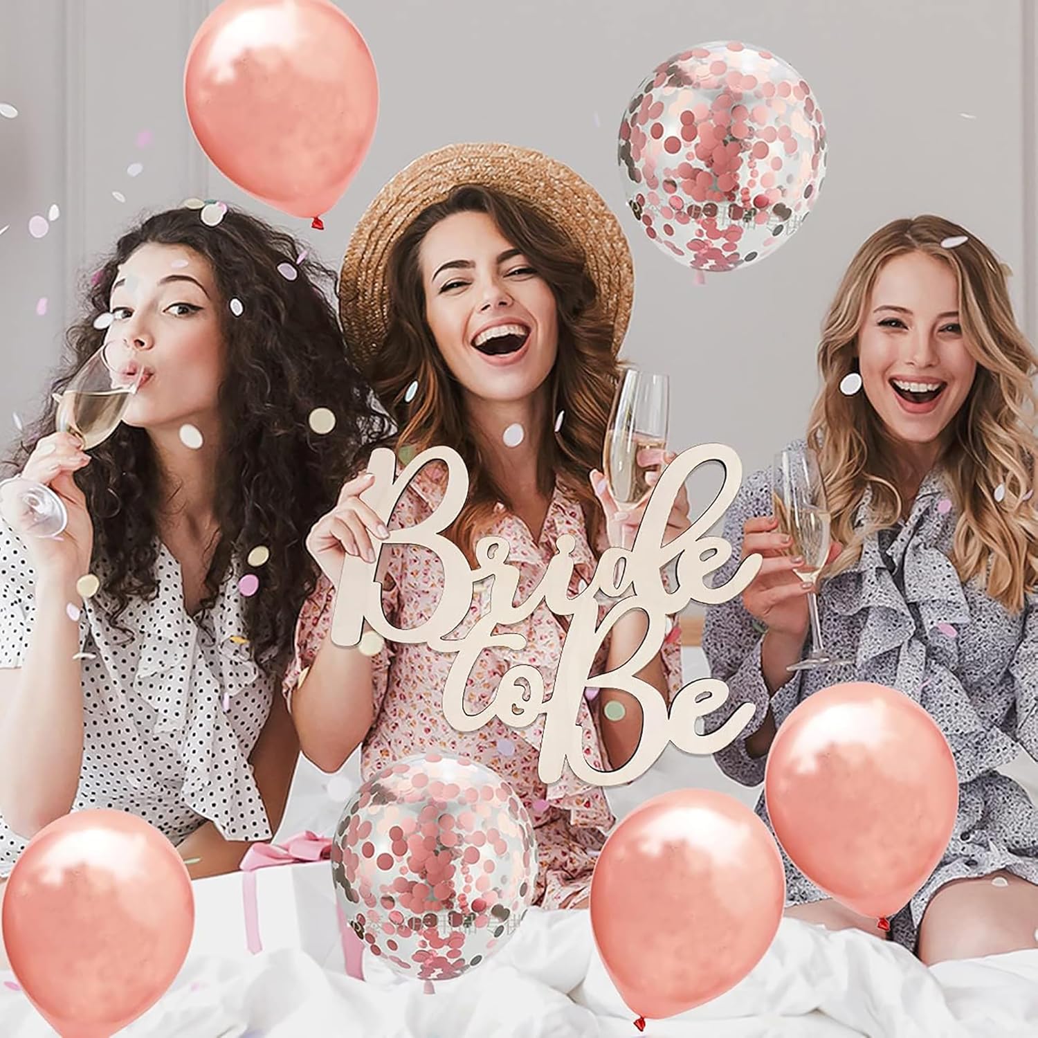 Three women celebrating a bridal shower with balloons and 'Bride to Be' sign.