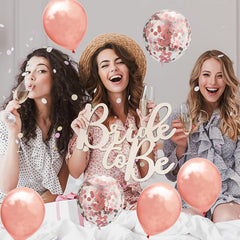 Three women celebrating a bridal shower with balloons and 'Bride to Be' sign.