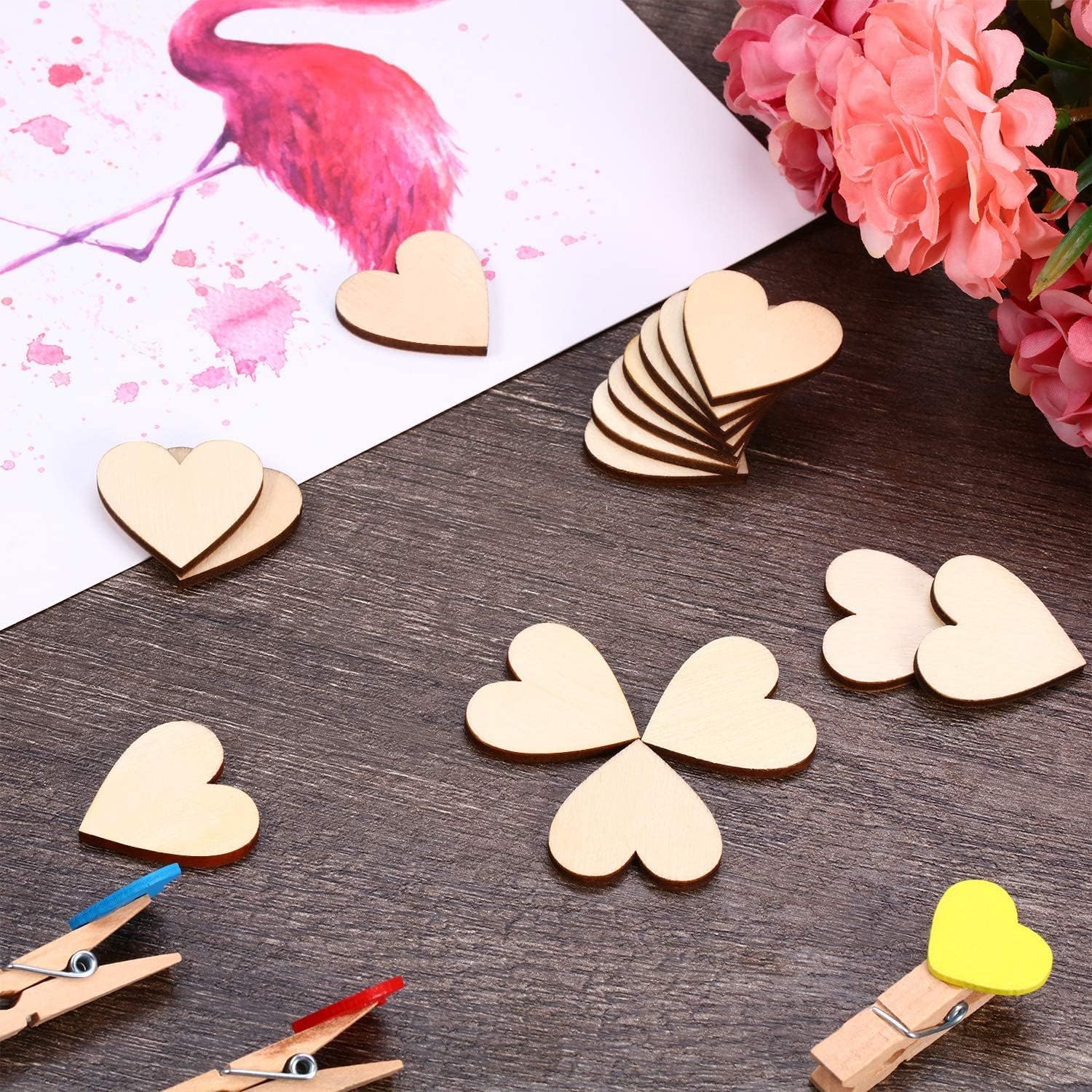 Wooden heart-shaped decorations on a wooden surface with flowers and clothespins.