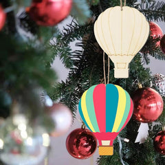 Colorful hot air balloon ornament hanging on a Christmas tree with red baubles.