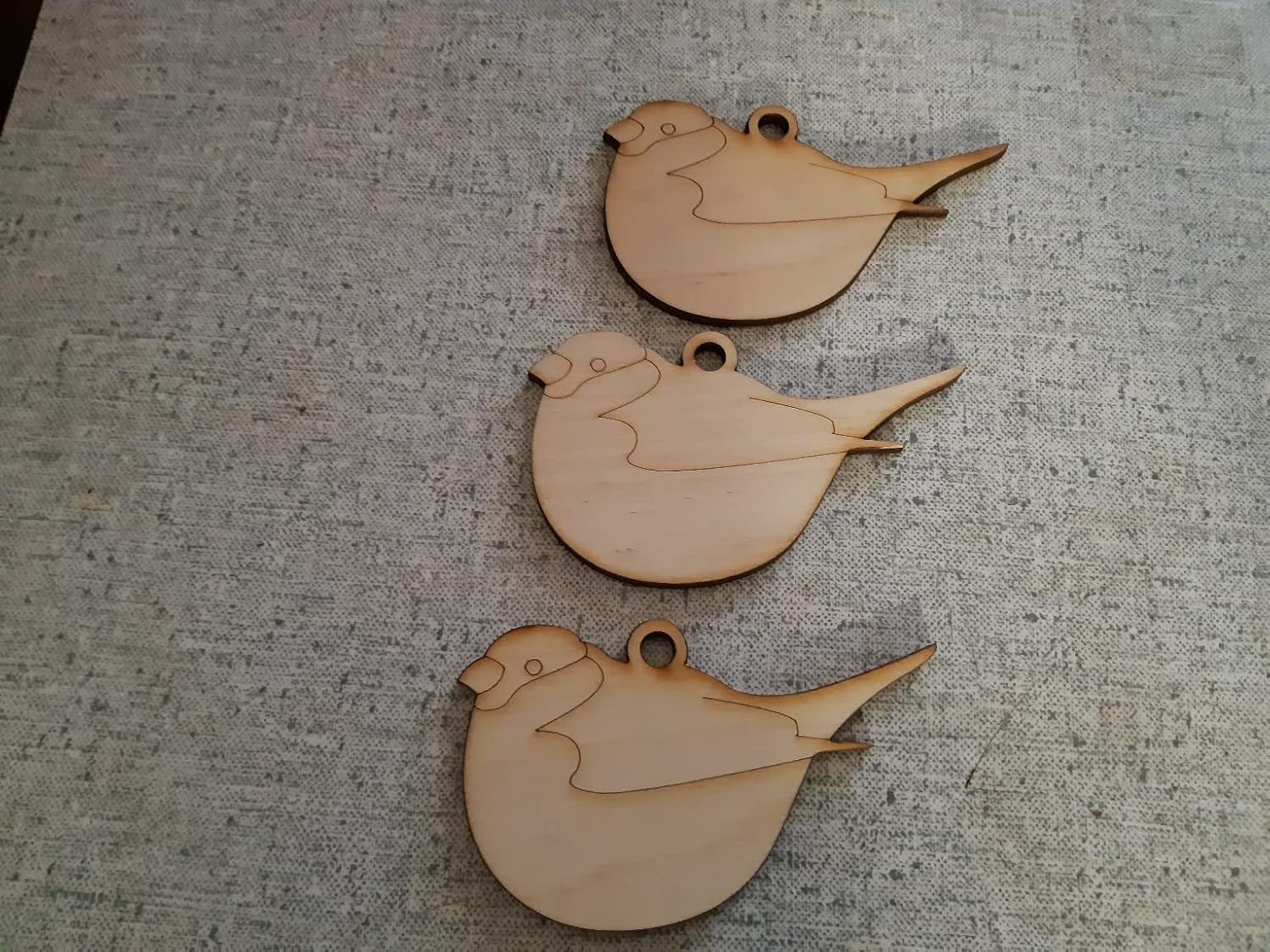 Three wooden bird-shaped ornaments on a textured surface