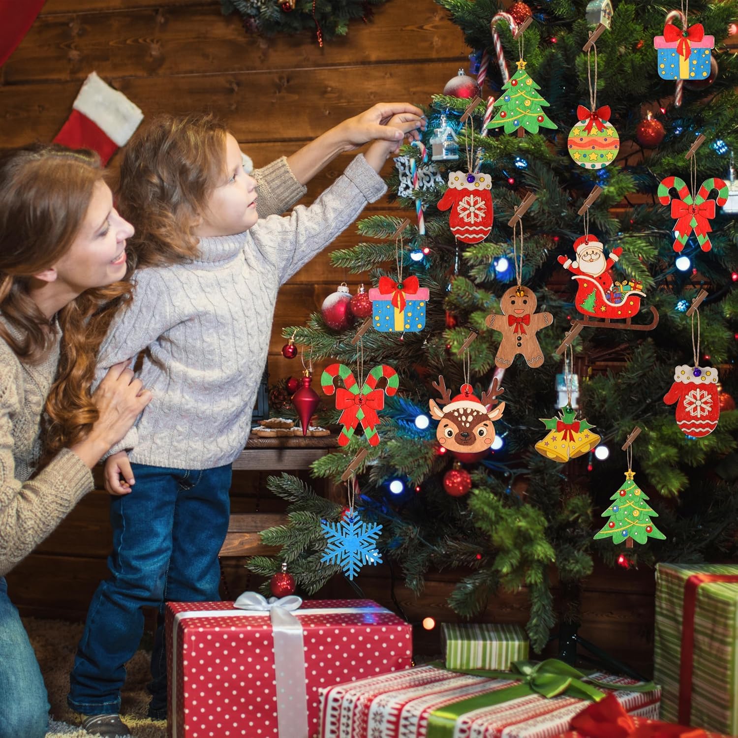 Woman and child decorating a Christmas tree with ornaments and presents underneath.
