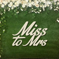 Decorative sign with 'Miss to Mrs' text on a green background with floral elements.