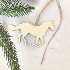 Wooden horse ornament hanging on a string with a green branch in the background