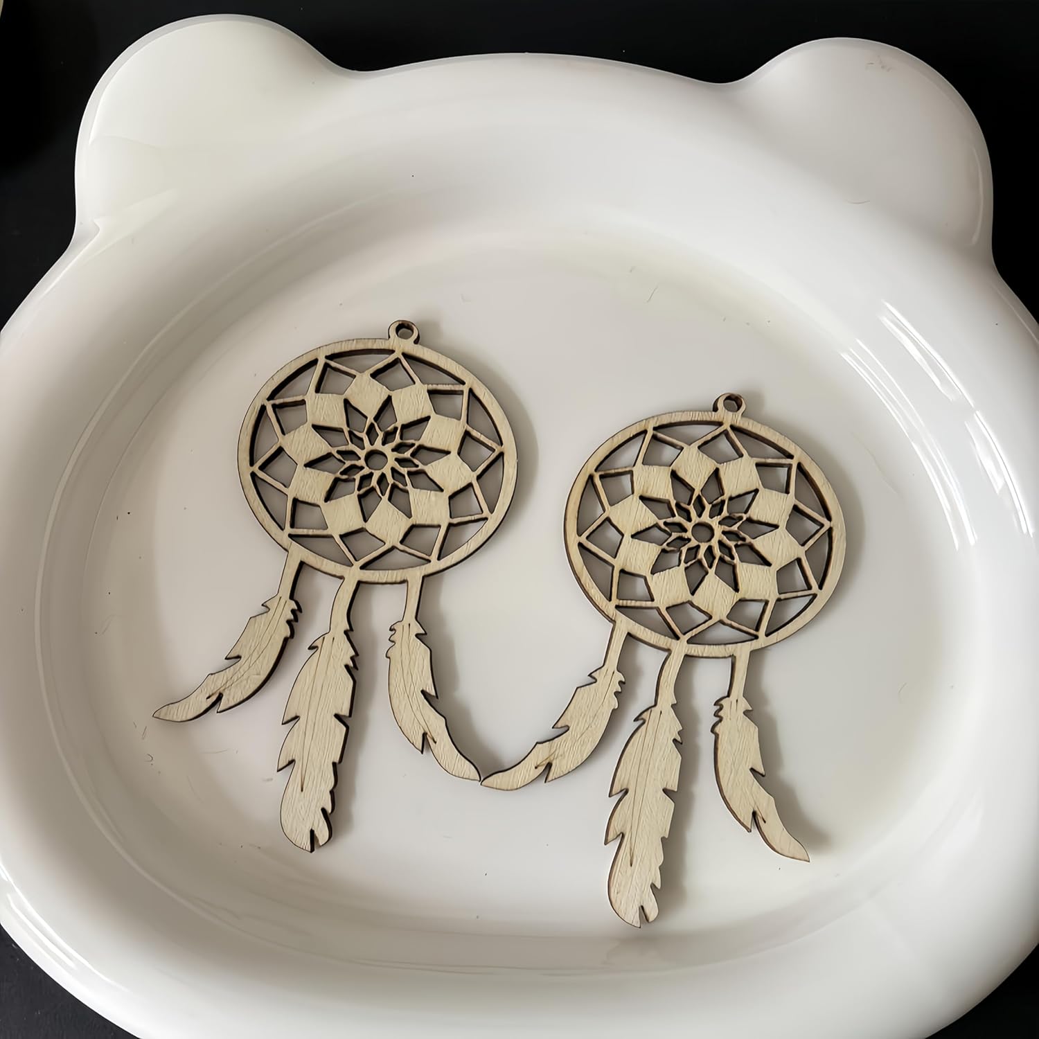 Two wooden dreamcatcher ornaments on a white ceramic dish.