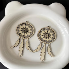 Two wooden dreamcatcher ornaments on a white ceramic dish.