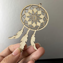 Wooden dreamcatcher ornament held in a hand against a neutral background