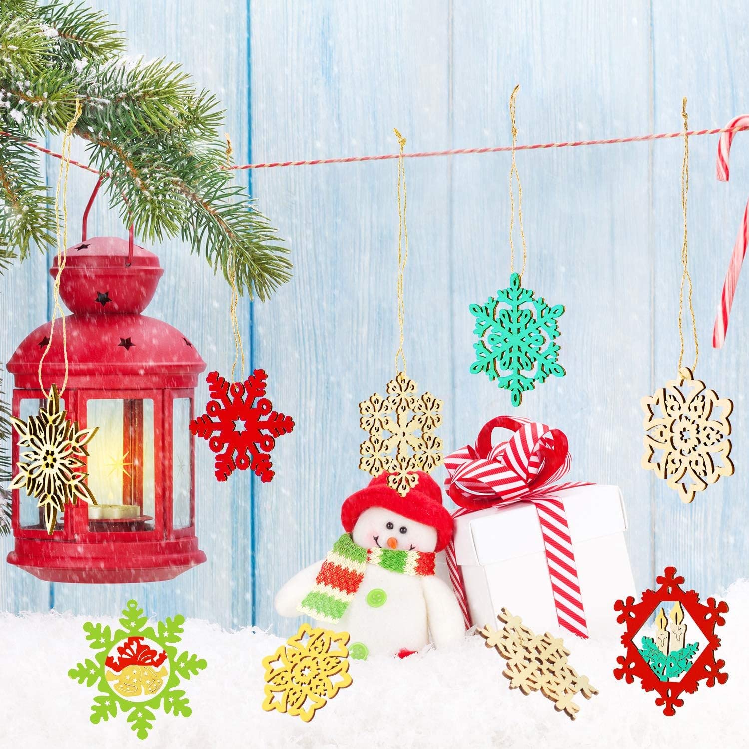 Decorative Christmas ornaments including a red lantern, snowflakes, a snowman, and a gift on a light blue wooden background.