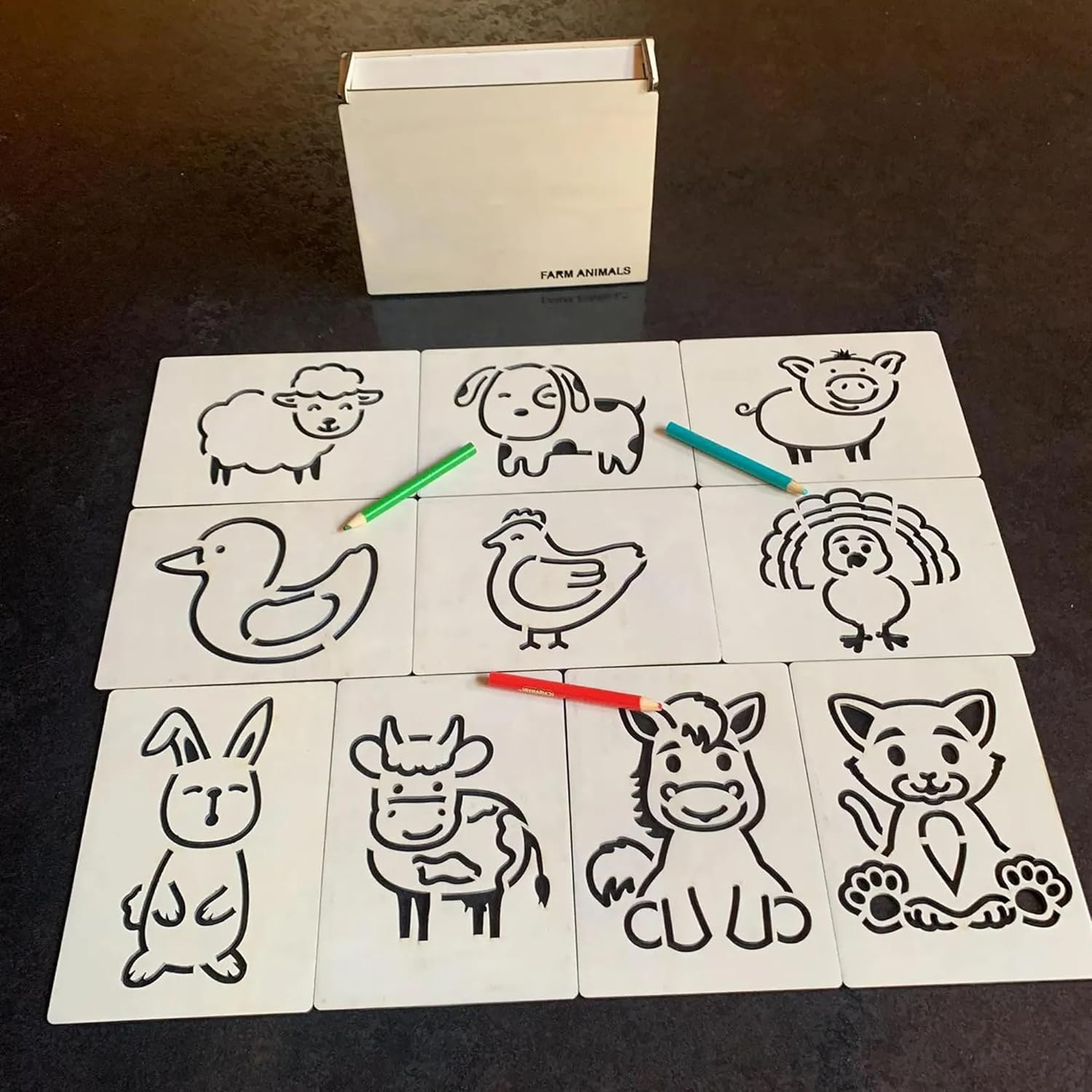 Set of farm animal coloring sheets with colored pencils on a dark surface