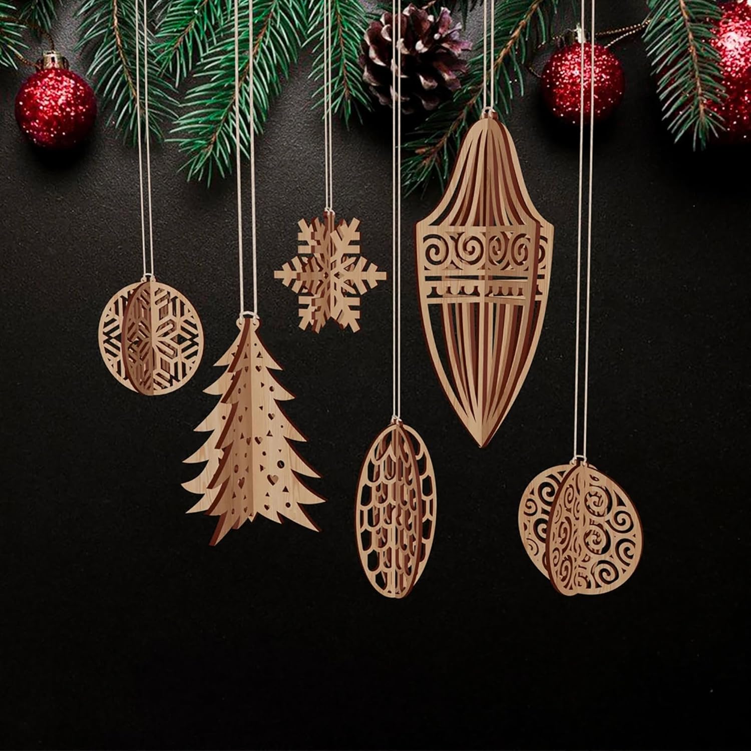 Wooden Christmas ornaments on a dark background with pine branches and red ornaments.