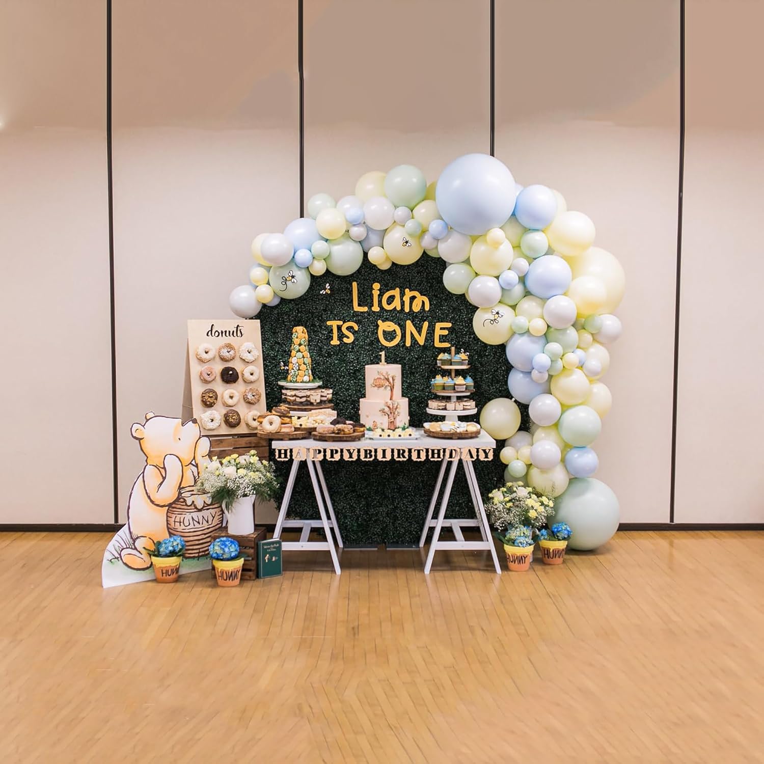 First birthday party setup with balloons, cake, and Winnie the Pooh decorations.