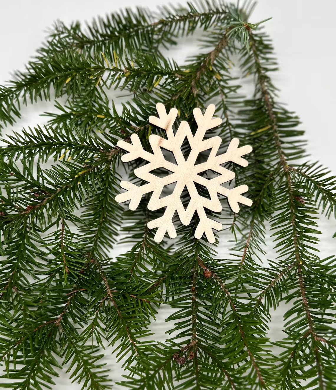 White snowflake ornament on a branch of green pine needles
