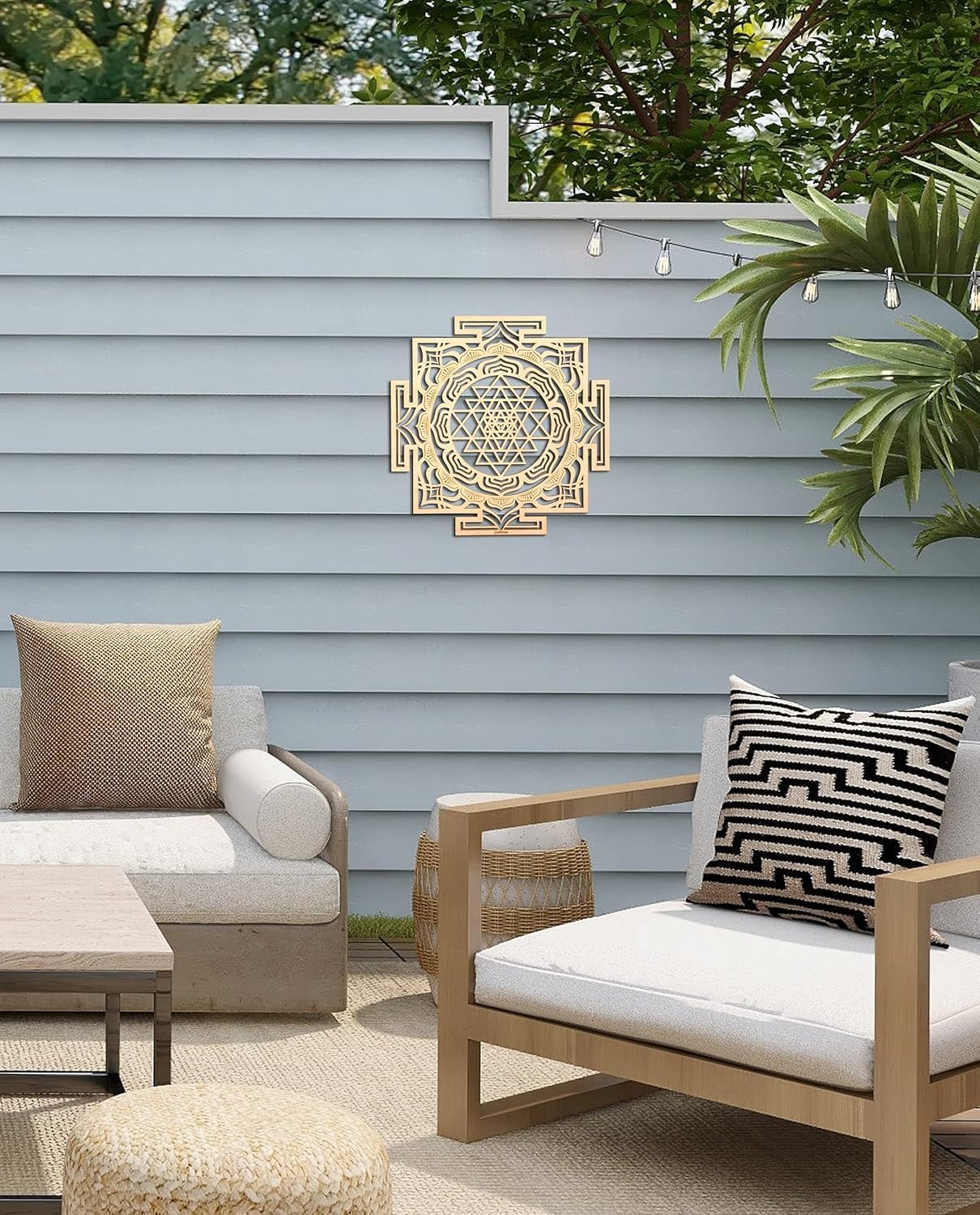 Outdoor patio with wooden furniture, cushions, and decorative wall art against a light blue wall.