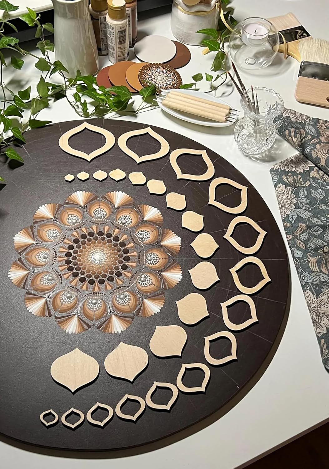 Decorative round tray with geometric patterns on a table with greenery and candles.