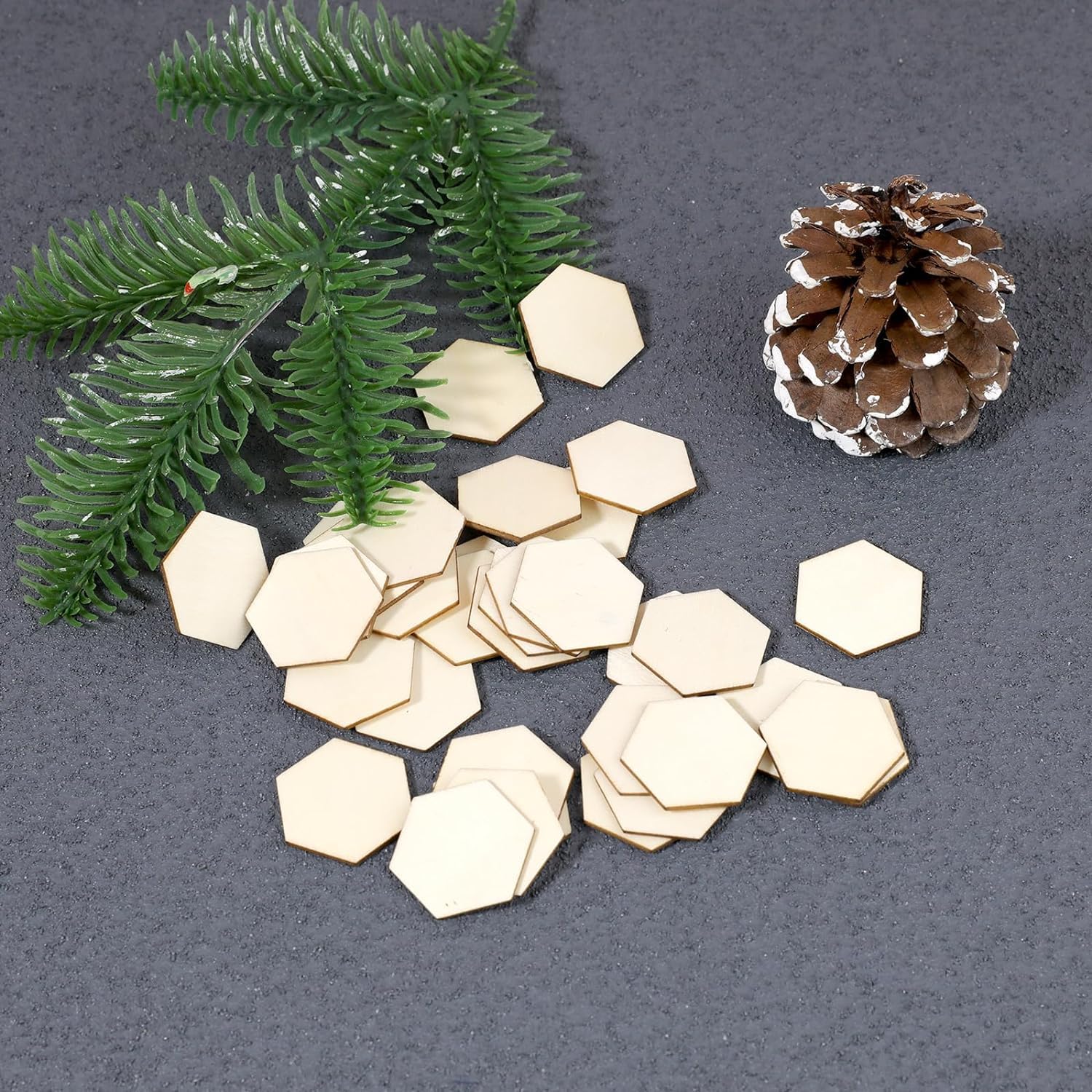 Hexagonal wooden pieces with a pine cone and greenery on a gray background