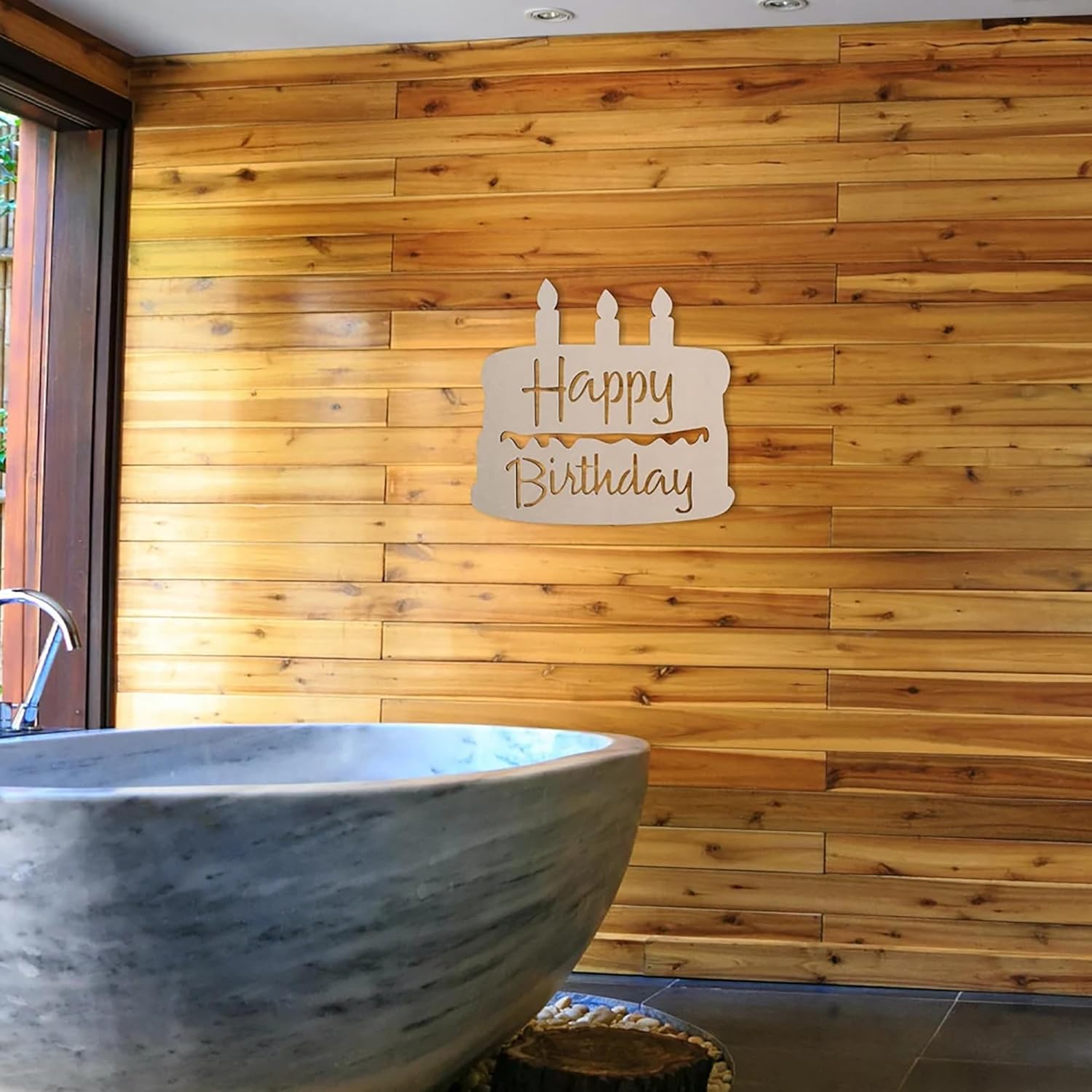 Wooden 'Happy Birthday' sign on a wooden wall with a stone bathtub in the foreground.