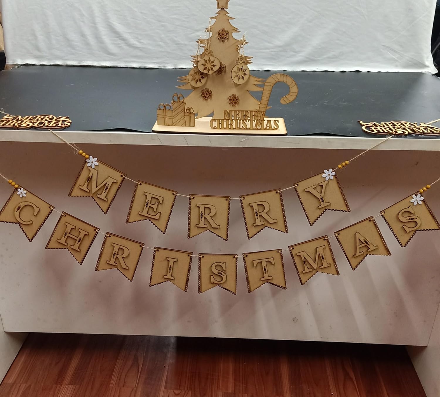 Merry Christmas banner with a wooden Christmas tree decoration on a table.
