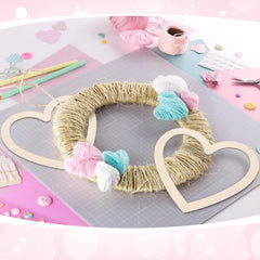Crafting project with yarn wreath and heart shapes on a pink and gray surface