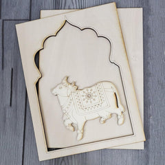 Decorative wooden cutout of a cow with intricate patterns on a gray surface