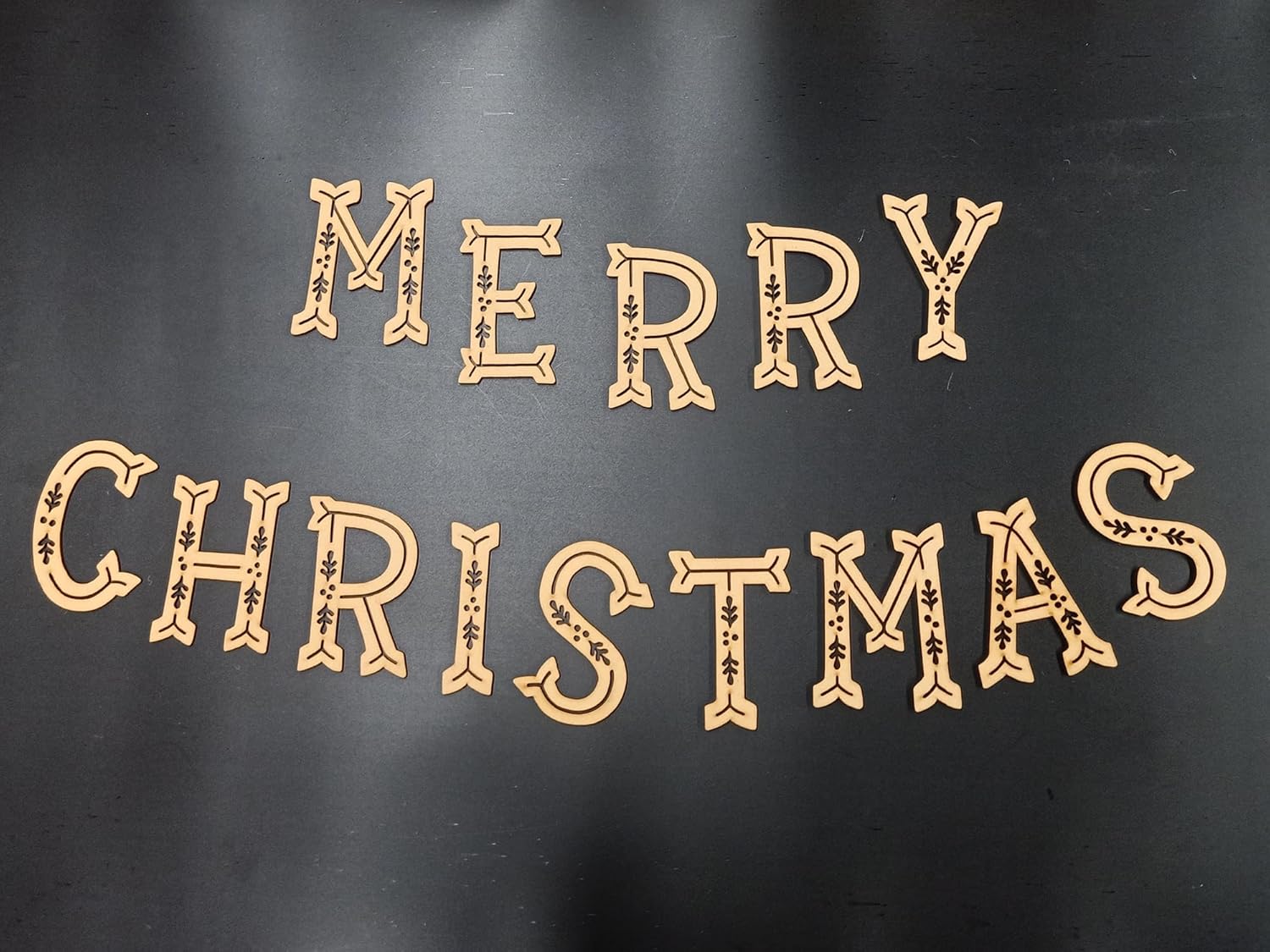 Decorative wooden letters spelling 'Merry Christmas' on a dark background