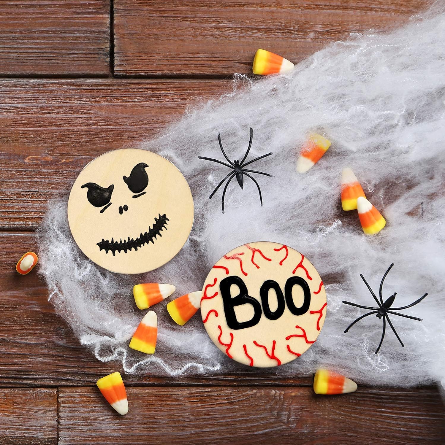 Halloween-themed decorations including a jack-o'-lantern face, 'BOO' sign, candy corn, and spiders on a wooden surface.