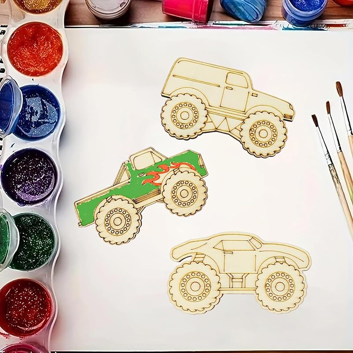 Wooden toy trucks on a white surface with paint containers and brushes.