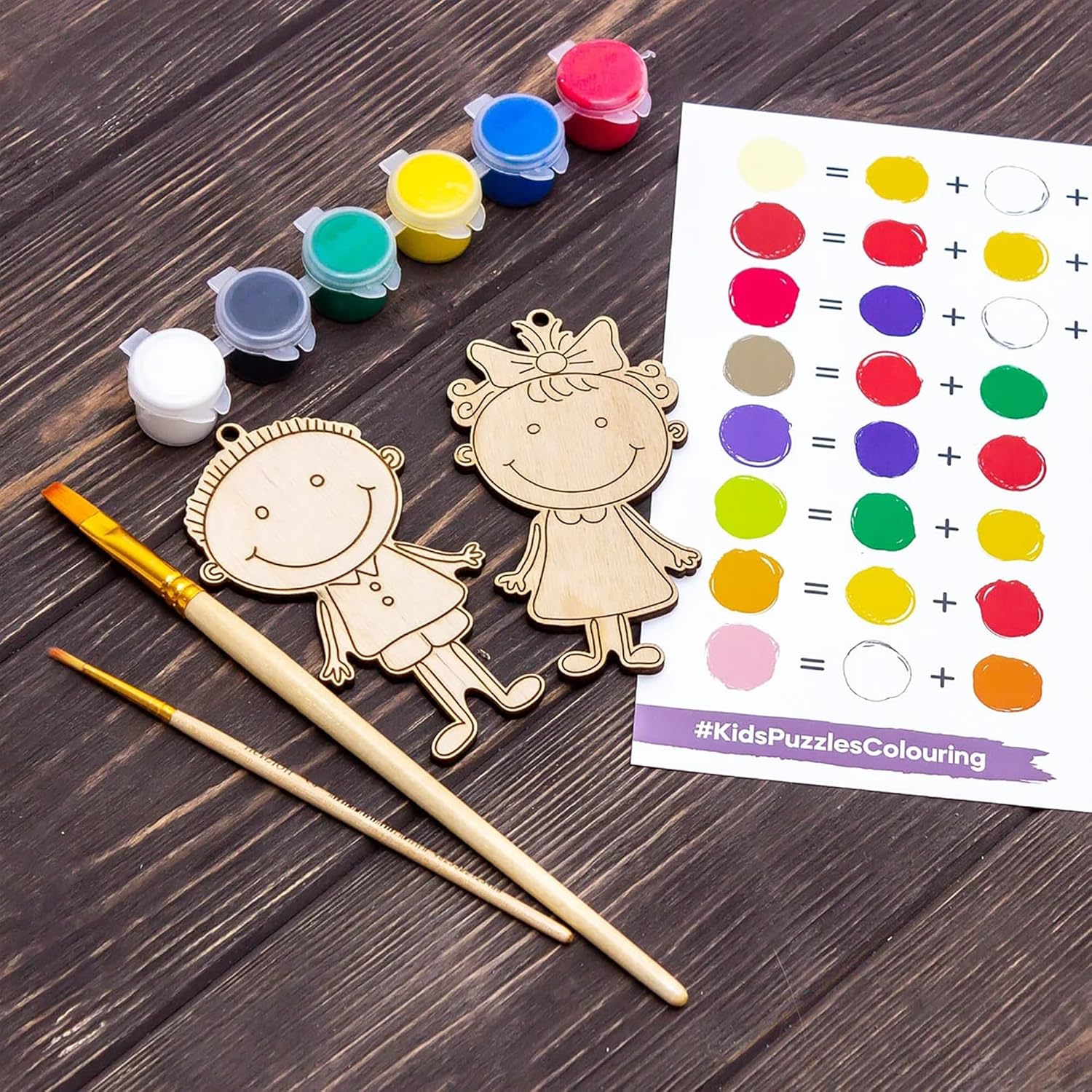 Wooden stick figure toys with paint, brushes, and color chart on a wooden surface