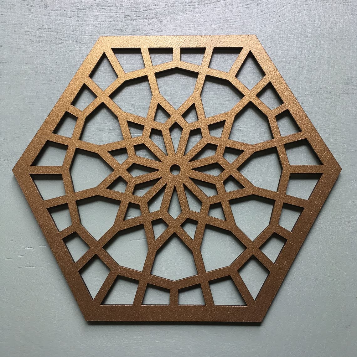 Decorative metal hexagonal panel with intricate cut-out pattern on a gray background