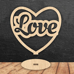 Wooden heart-shaped sign with 'Love' engraved on a dark surface