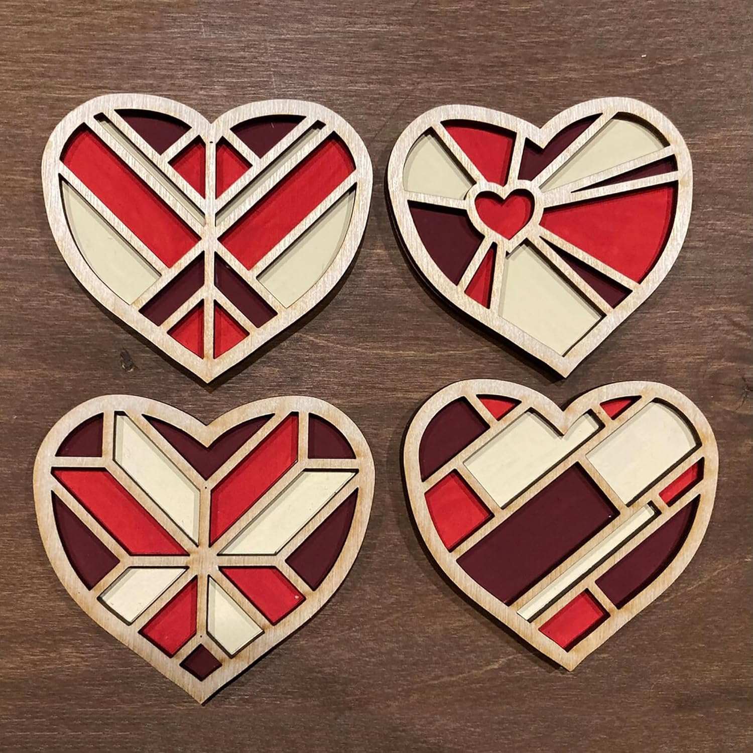 Four geometric heart-shaped wooden decorations on a wooden surface