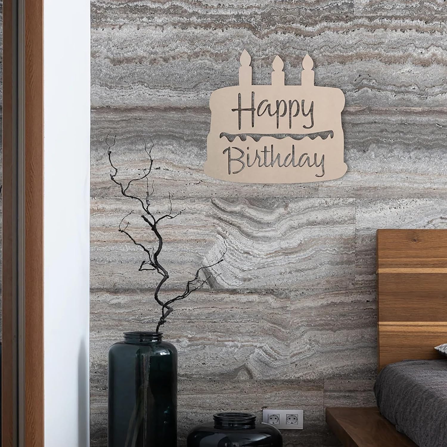 Decorative 'Happy Birthday' sign on a marble wall with a vase and plant in the foreground.