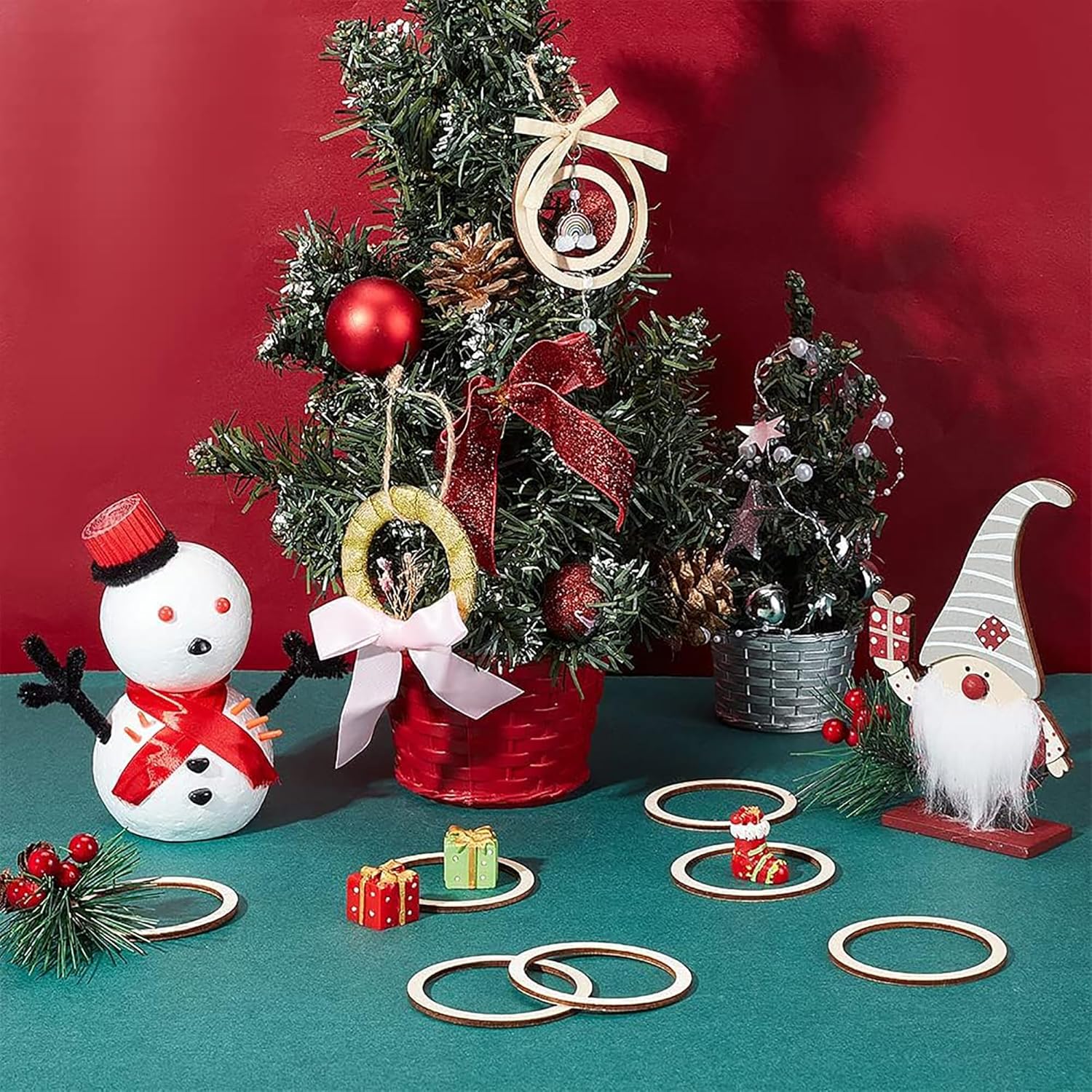 Decorative Christmas scene with small trees, ornaments, and a snowman on a red background.